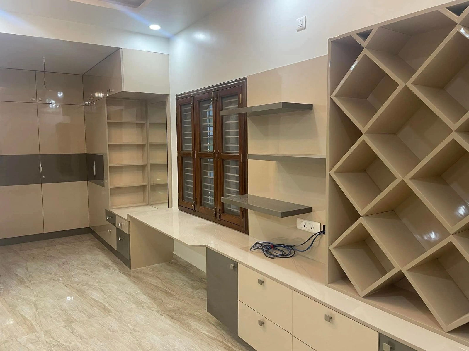 A study wall in cream laminate: a long desk with drawers, floating shelves, tall cabinets and diagonal criss-cross shelving.